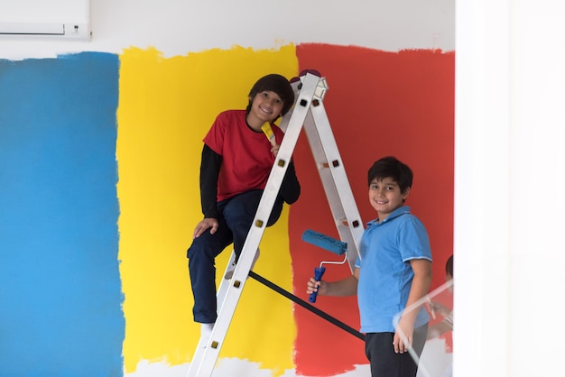 a group of young boys helps to paint a wall in new home