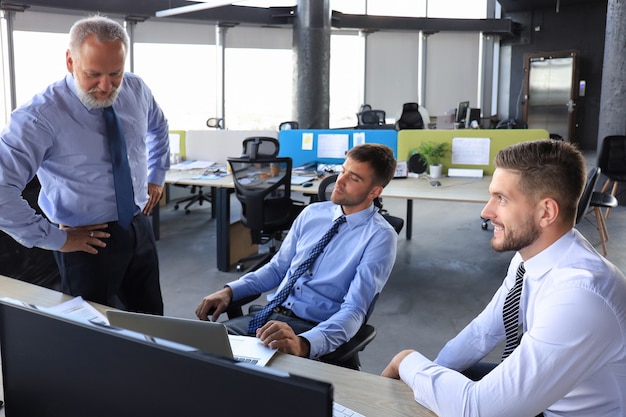 Group of young business men in formalwear working using computers while sitting in the office.