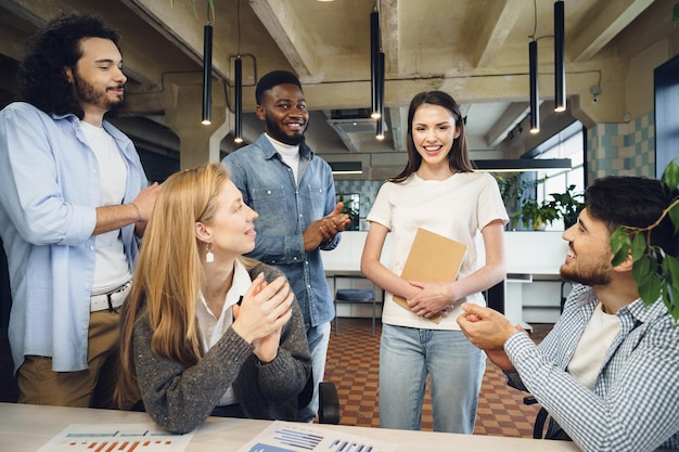 Group of young business people applaud their female colleague after presentation