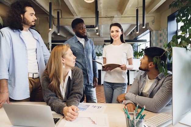 Group of young business people discussing documents during meeting in office