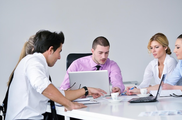 Group of young business people sitting in board room during meeting and discussing with paperwork