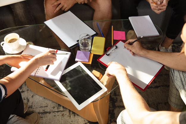 Group of young caucasian office workers meeting to discuss new ideas. Creative meeting. Teamwork and brainstorming. Men and women meet in office to plan their future working. Business concept.