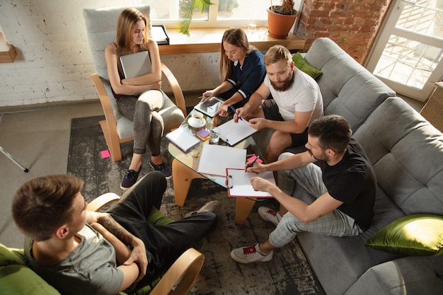 Group of young caucasian office workers meeting to discuss new ideas. Creative meeting. Teamwork and brainstorming. Men and women meet in office to plan their future working. Business concept.