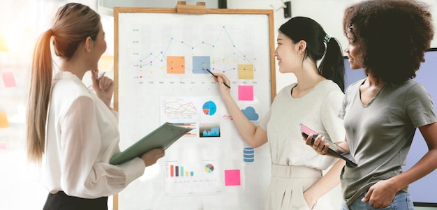 Group of young confident business people analyzing data using graph chart standing in office