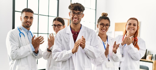 Group of young doctor smiling happy and clapping standing at the clinic office.