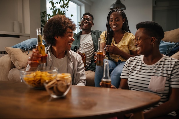 Group of young friends enjoying drinks at home during weekend