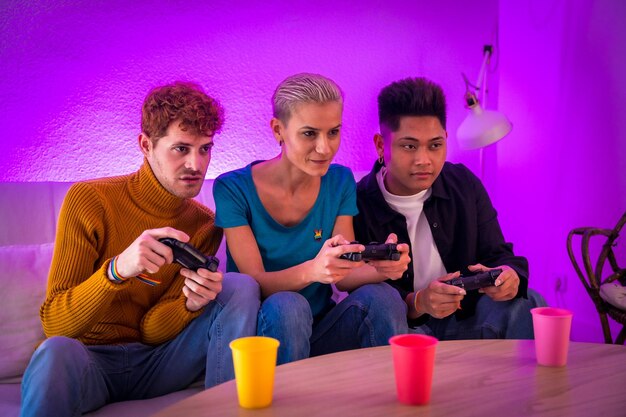 Group of young friends play video games together on the sofa at home