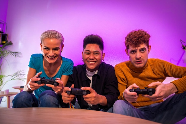 Group of young friends playing video games together on the sofa at home portrait looking at camera