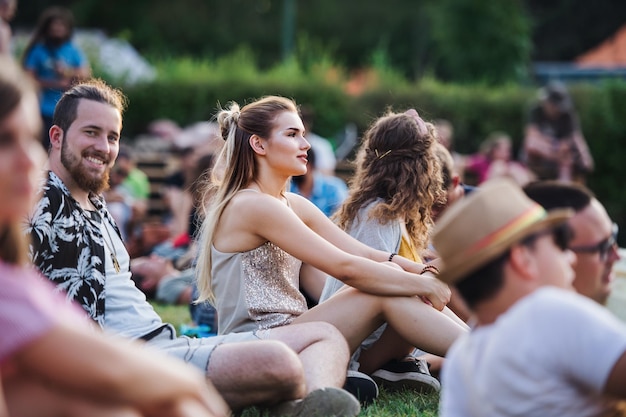 Photo group of young friends sitting on ground at summer festival