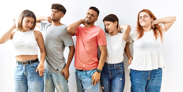 Group of young friends standing together over isolated background suffering of neck ache injury, touching neck with hand, muscular pain