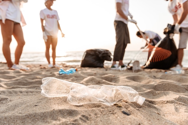 Group of young friends volunteers cleaning beach from plastic garbage