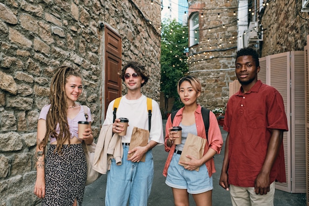 Group of young intercultural friends with drinks and snacks