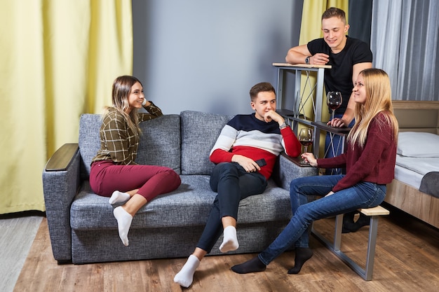 Group of young men and women of student age  while sitting on sofa in youth hostel.