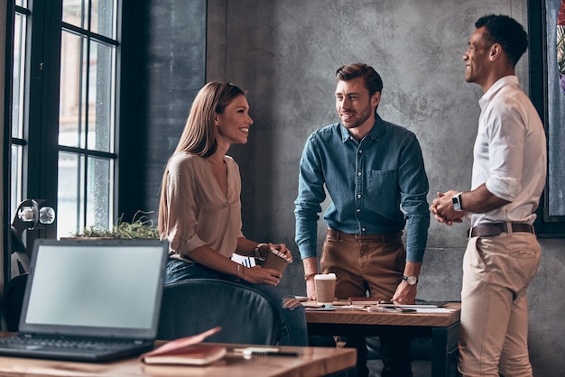 group of young modern people in smart casual wear discussing business and smiling 