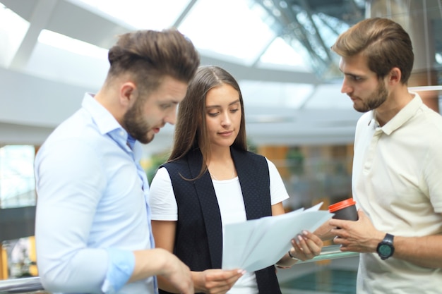 Group of young modern people in smart casual wear having a brainstorm meeting while standing in the creative office.