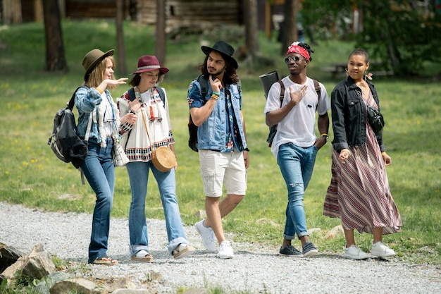 Group of young multi-ethnic friends walking path together and talking while enjoying weekends at festival campsite