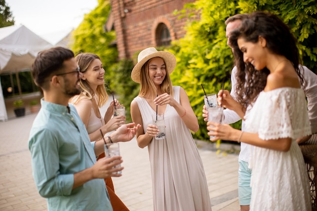 A group of young people gather outdoors to enjoy each other's company and refreshing glasses of lemonade