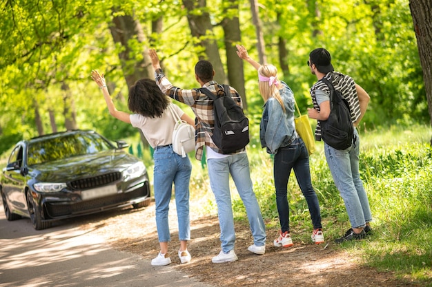 Group of young people hitchiking on the road