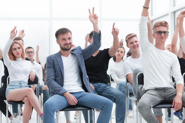 Group of young people raising their hands to ask a question