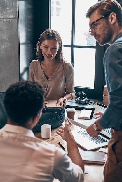 Group of young people in smart casual wear discussing business while working in the office