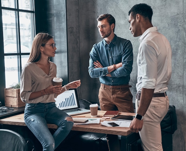 Group of young people in smart casual wear discussing business while working in the office