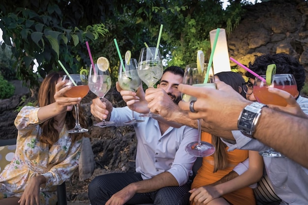 Group of young people who gather on the terrace garden for a cocktail party raising their glasses