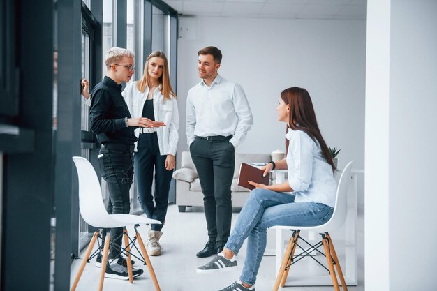 Group of young positive team have work and communicating together indoors in office near windows