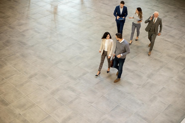 A group of young and senior business people are walking in an office hallway