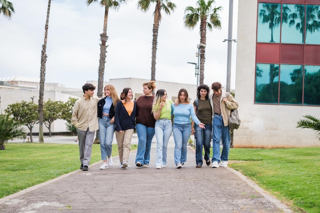 Group of young students walking through the university walks next to the library