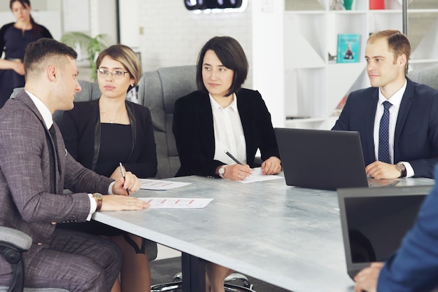 Group of young successful businessmen lawyers communicating together in a conference room while working on a project