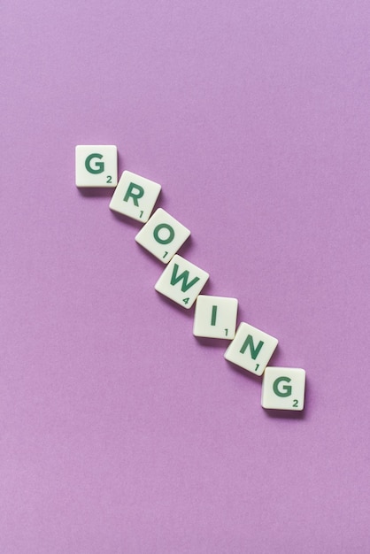 Growing formed of scrabble blocks on lilac background