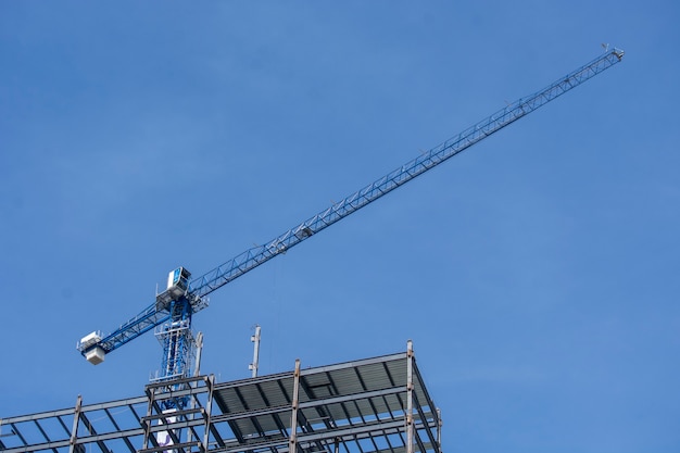 Grua de pluma en construccion con el cielo azul de fondo