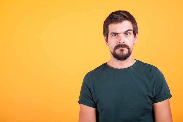 Grumpy stressed worried man on yellow background lookin at the camera. Depression, unhappy and stress concept image