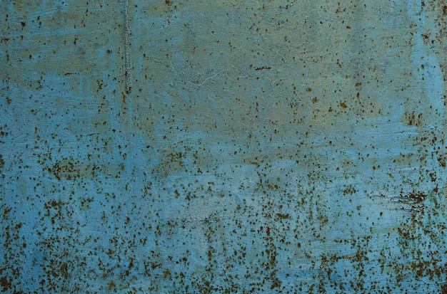 Grunge background with old peeling blue paint. Corrosion of iron with streaks of rust.