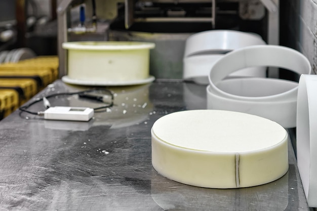 Photo gruyere de comte cheese in the special forms at the dairy in franche comte, burgundy, in france. as a part of the process of production