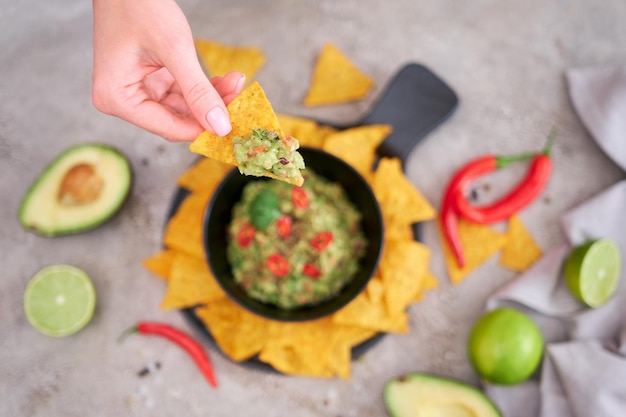 Guacamole dip with tortilla chips or nachos on black serving board