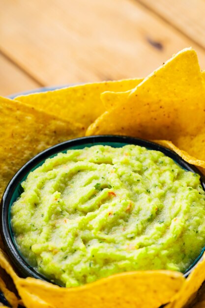 Guacamole sauce and nacho chips. Tortilla chips and Mexican guacamole sauce in a bowl. Close-up