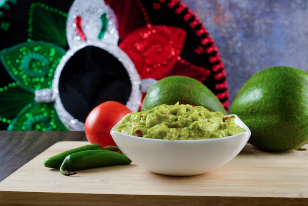 Guacamole served on a white plate on a wooden table. Guacamole ingredients.