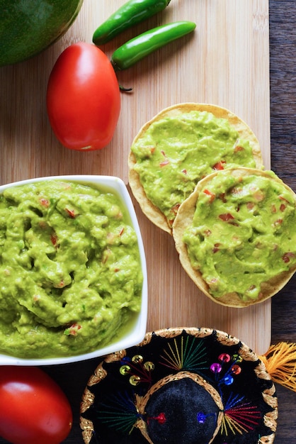 Guacamole served on a white plate on a wooden table. Guacamole ingredients.