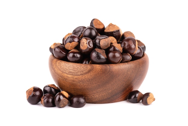 Guarana seed in wooden bowl isolated on white surface