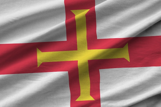 Guernsey flag with big folds waving close up under the studio light indoors The official symbols and colors in banner