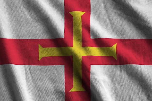 Guernsey flag with big folds waving close up under the studio light indoors The official symbols and colors in banner