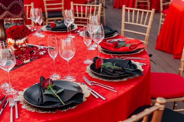 Guests table setting for banquet in black red and gold style elegant dinner decor tablecloth plates