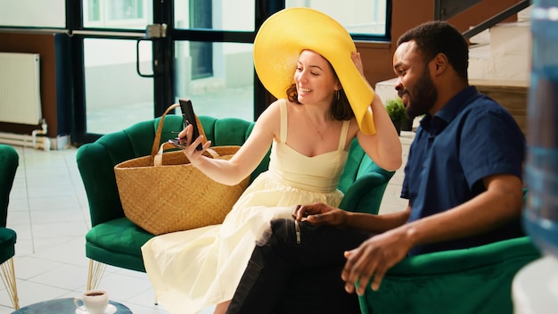 Guests using videocall meeting in lobby talking to friends after they arrive on honeymoon tropical trip Diverse people enjoying videoconference chat online hotel lounge area