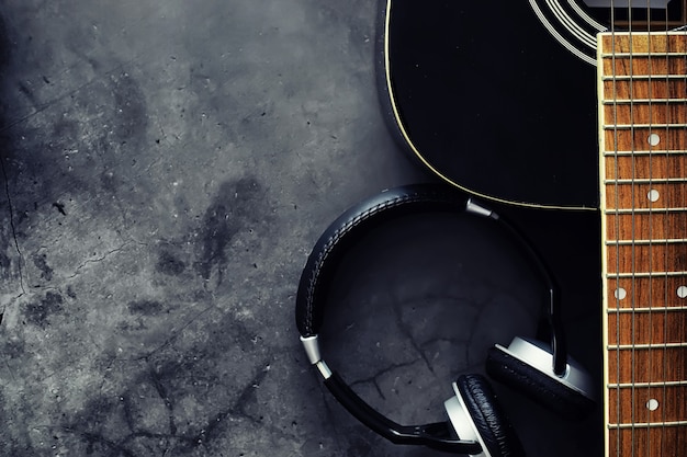 Guitar and accessories on a stone background. Desk musician, headphones, microphone and more.