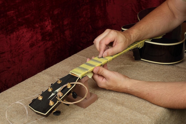 Guitar repair and service Worker polishing guitar neck frets Sandpaper