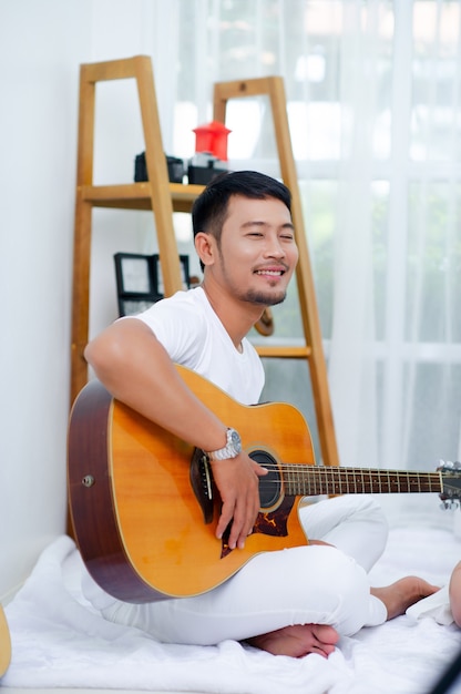 The guitarist, the man sitting smiling happily.