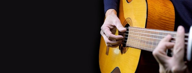 Guitarist playing acoustic guitar on black background selective focus Long wide banner copy space