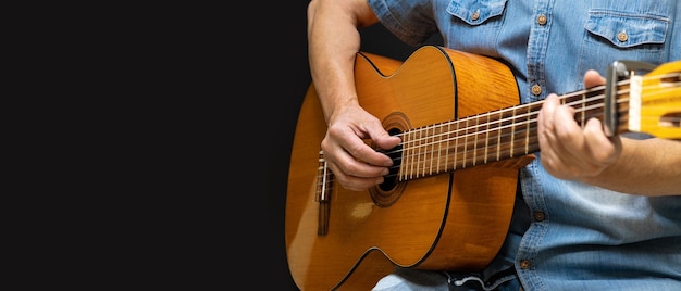 Guitarist playing acoustic guitar on black background selective focus A man playing acoustic guitar