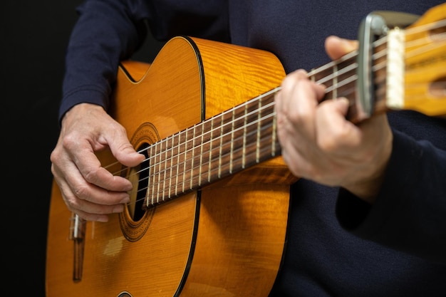 Guitarist playing acoustic guitar on black background selective focus A man playing acoustic guitar